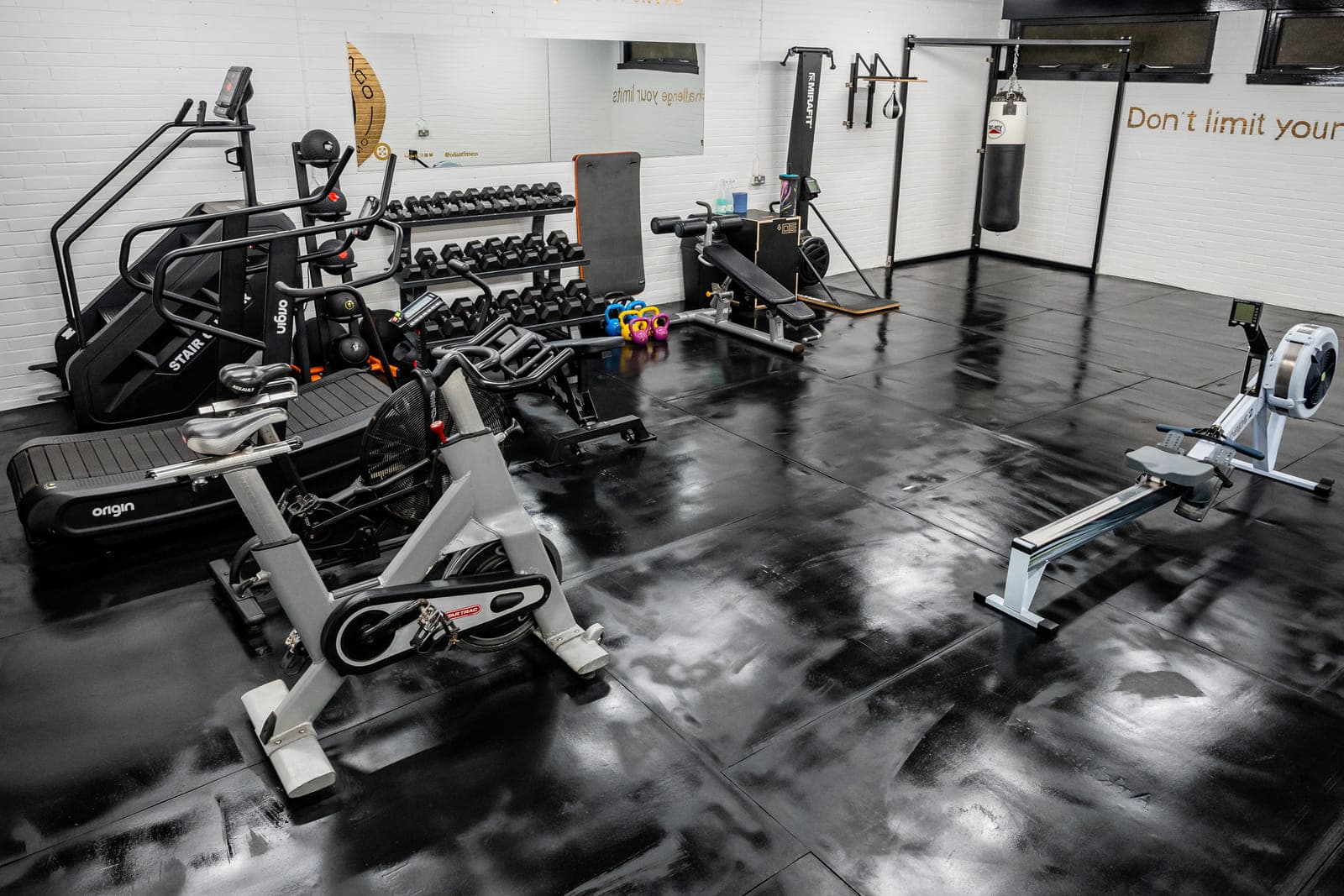The cardio area at ODAAT Fitness — a spin bike, curved treadmill, stair climber and Concept2 rower, with a punch bag hanging at the far wall