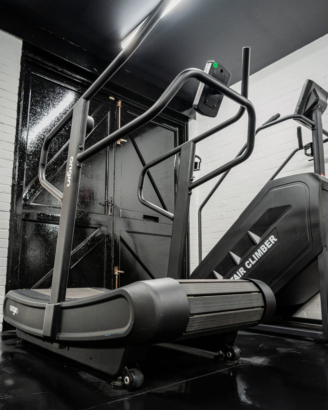 A self-powered curved treadmill beside a stair climber in the cardio corner of the gym