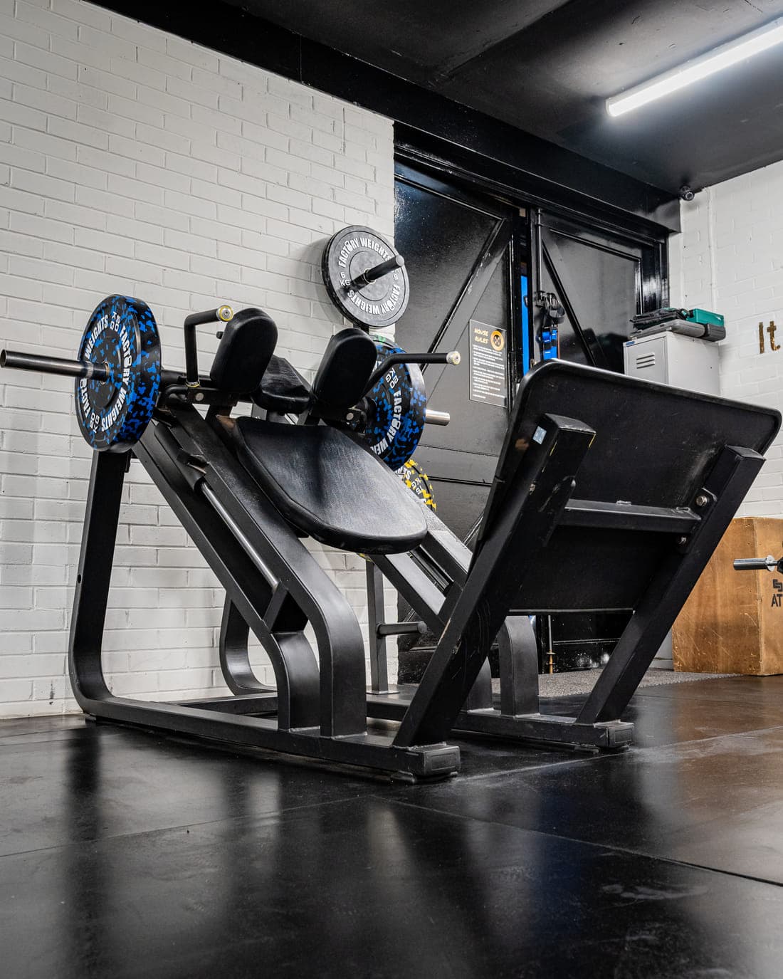 A plate-loaded leg press machine with Olympic plates racked on its posts